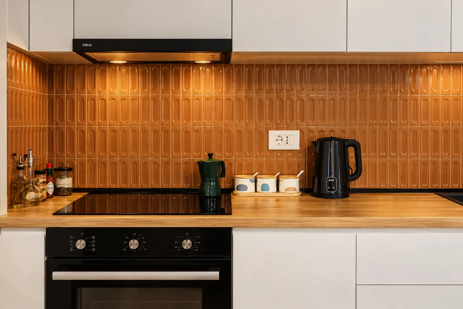 Kitchen worktop with electric hob, oven, kettle and moka pot.